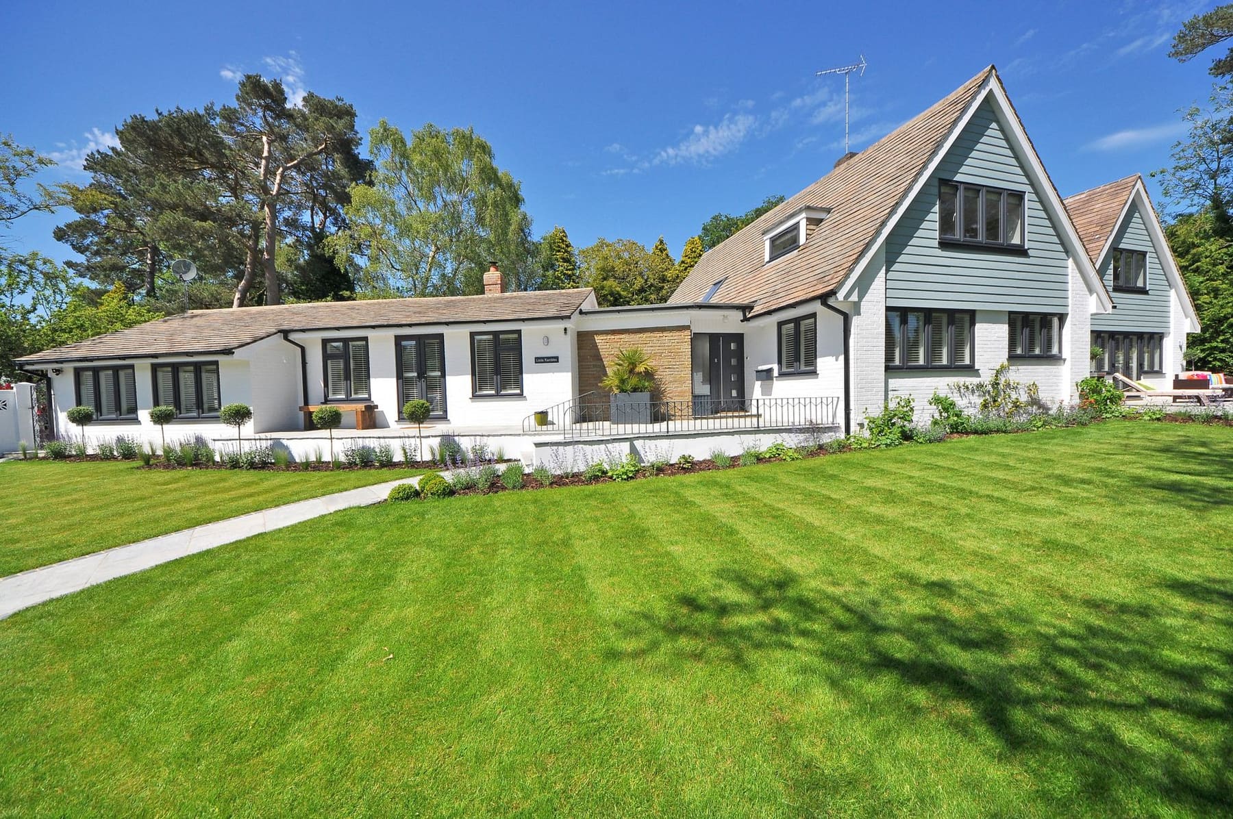 A suburban house with a neatly mown lawn under a blue sky