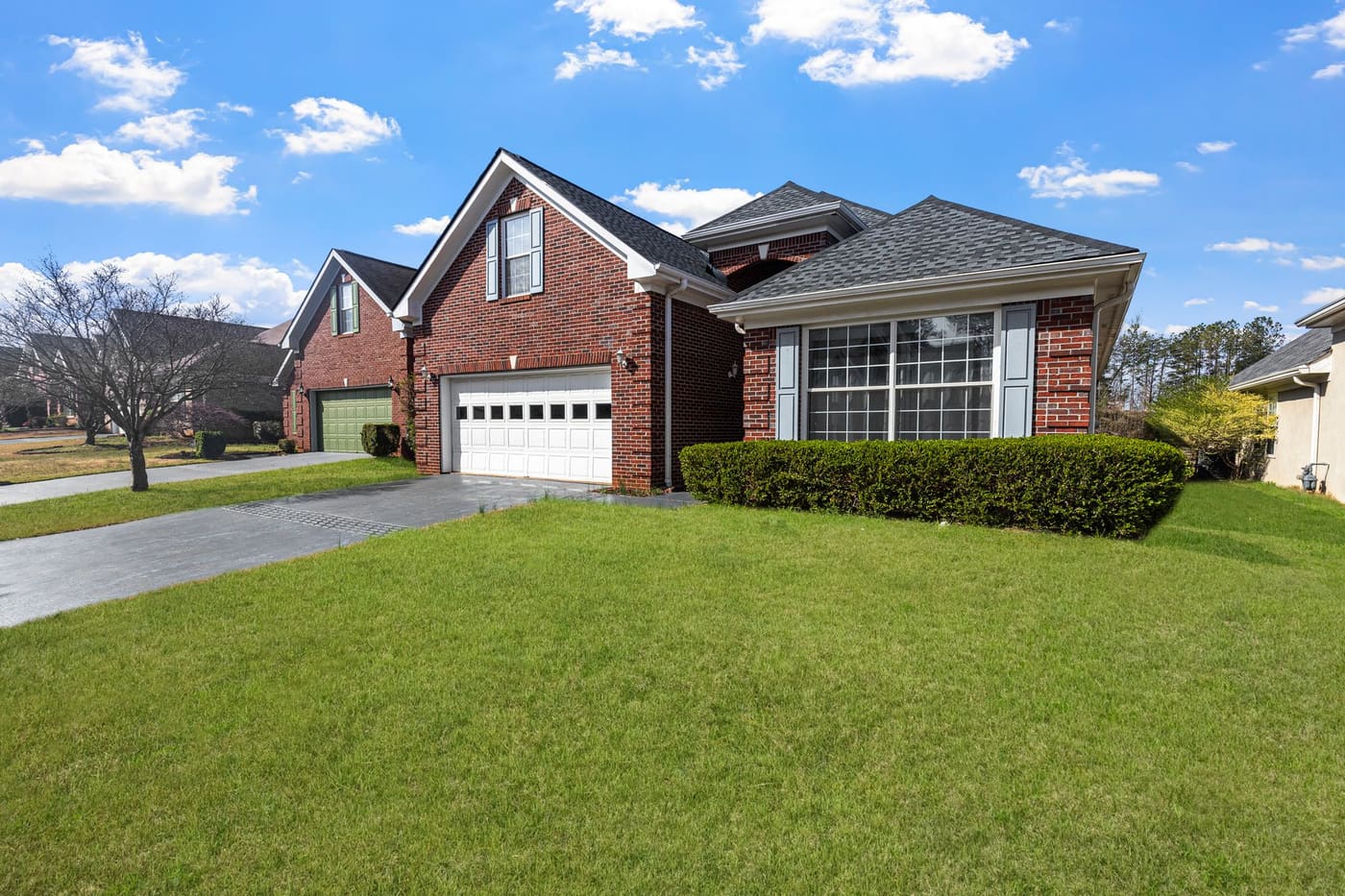 A red brick suburban house with a mown lawn under a blue sky