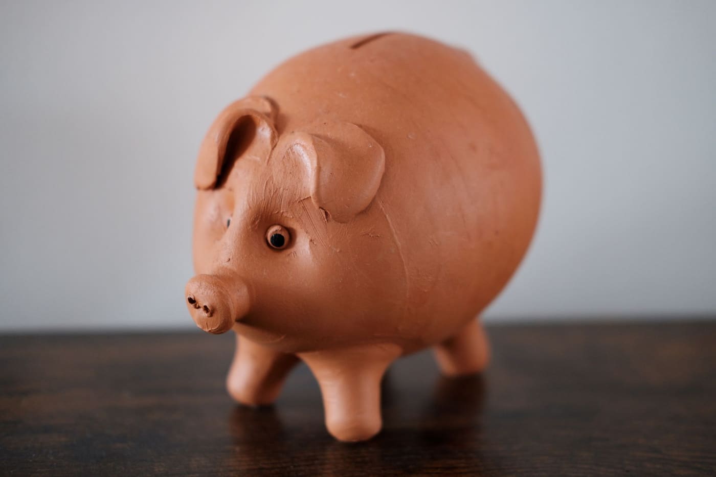 A terracotta piggy bank on a wooden table