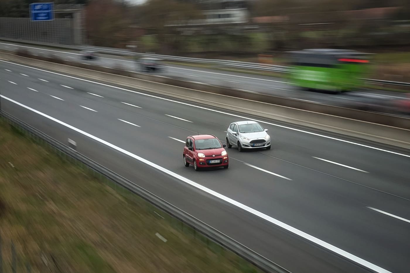 Two cars driving on a highway with the background blurred by motion